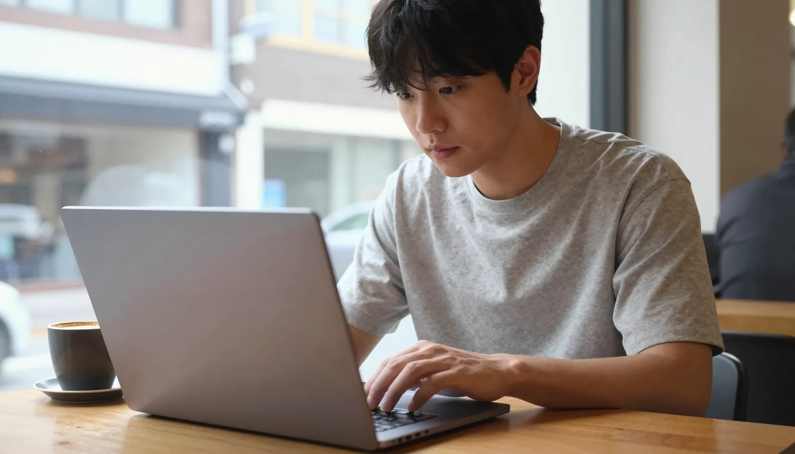 카페 창가에서 노트북으로 일하는 사람